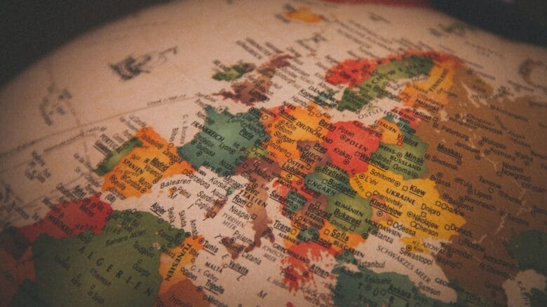 Et nærbillede af en vintage-klode, der fremhæver Europa, og viser lande i forskellige farver som grøn, rød og gul. Kortet har etiketter på forskellige sprog, der viser geografiske detaljer og kulturel mangfoldighed.